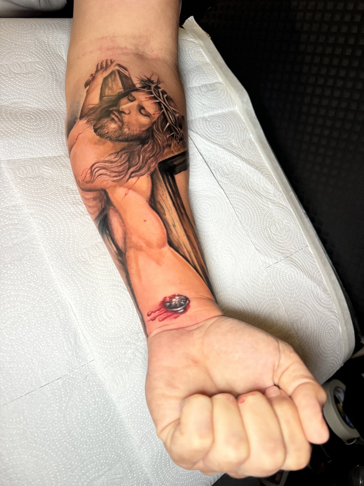 Cristo em realismo tatuado no antebraco